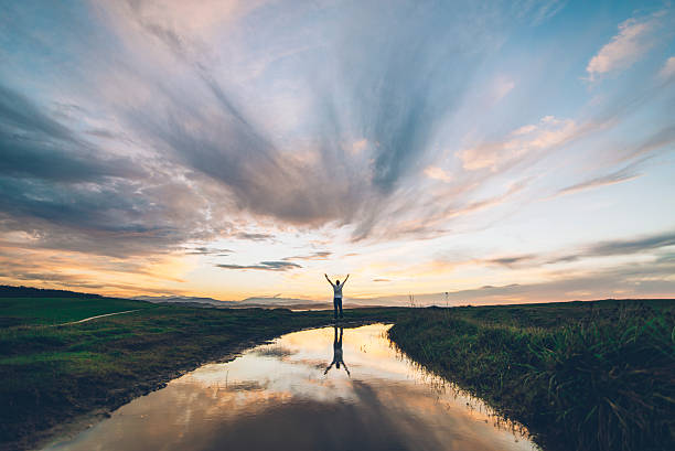 A young man reflected on a puddle at sunset